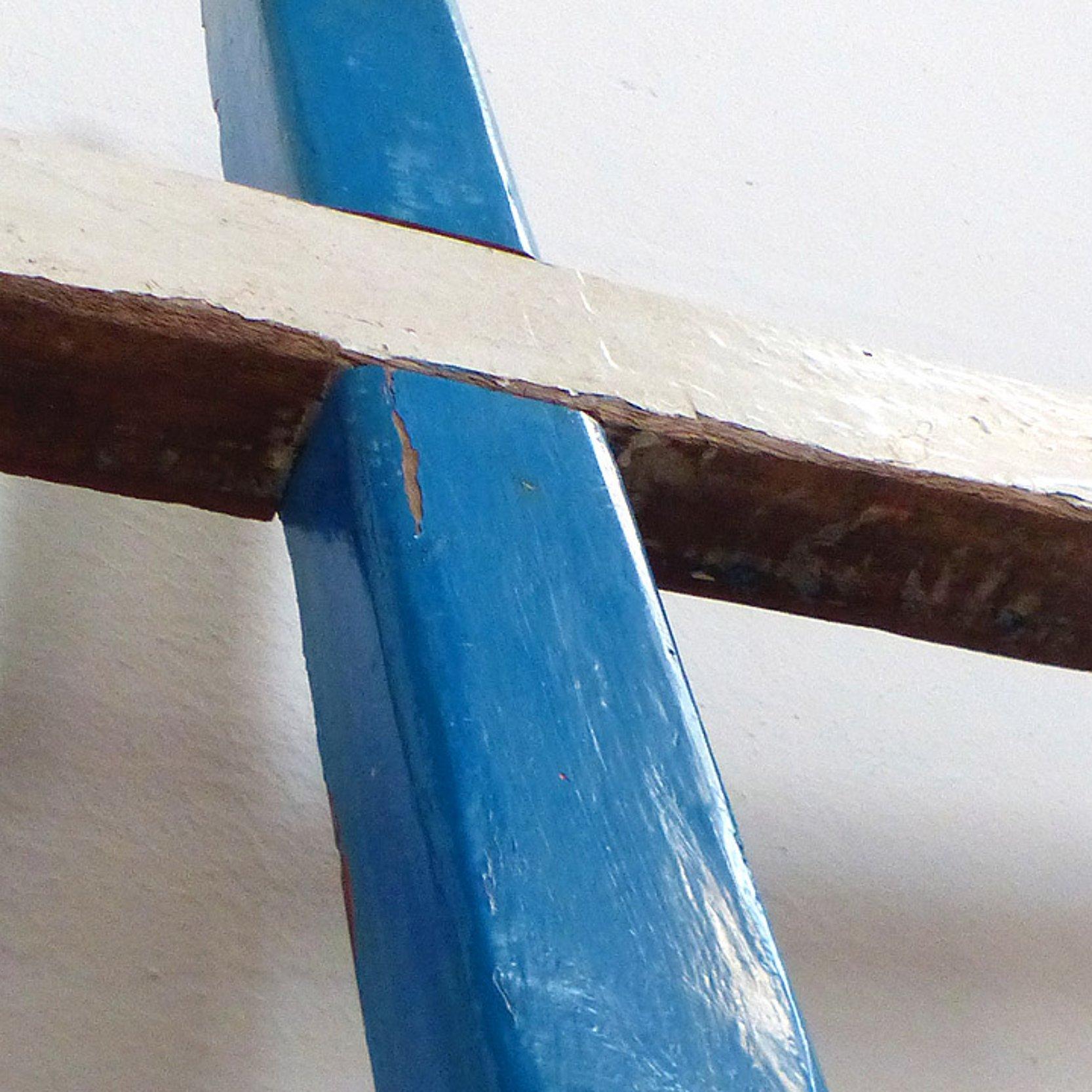 Ein Kreuz: Über einem senkrechten blauen Balken liegt ein brauner Holzbalken