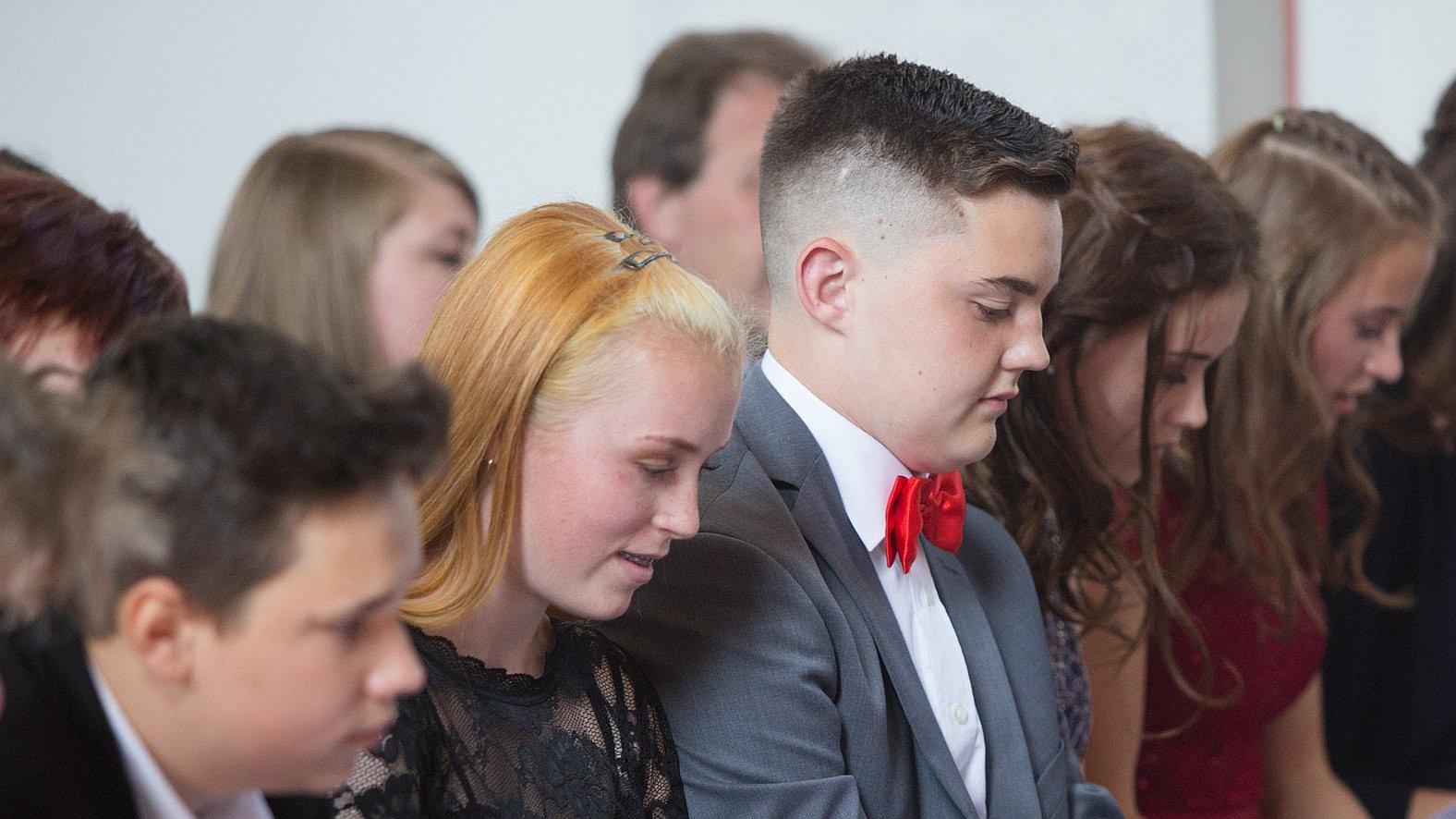 Jugendliche sitzen in einer Kirchenbank und singen