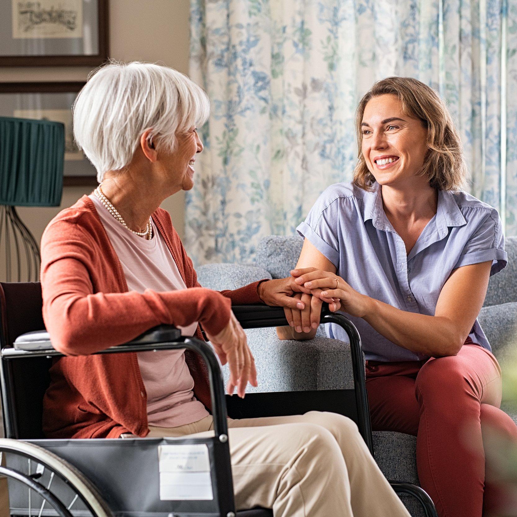alte Dame im Rollstuhl im Gespräch mit einer jüngeren Frau 