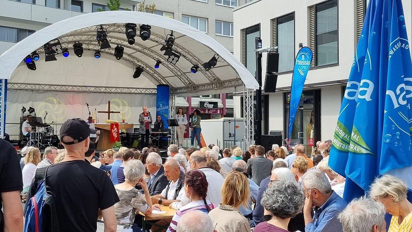 Viele Menschen sitzen vor einer Bühne, auf der ein Pfingstgottesdienst zelebriert wird