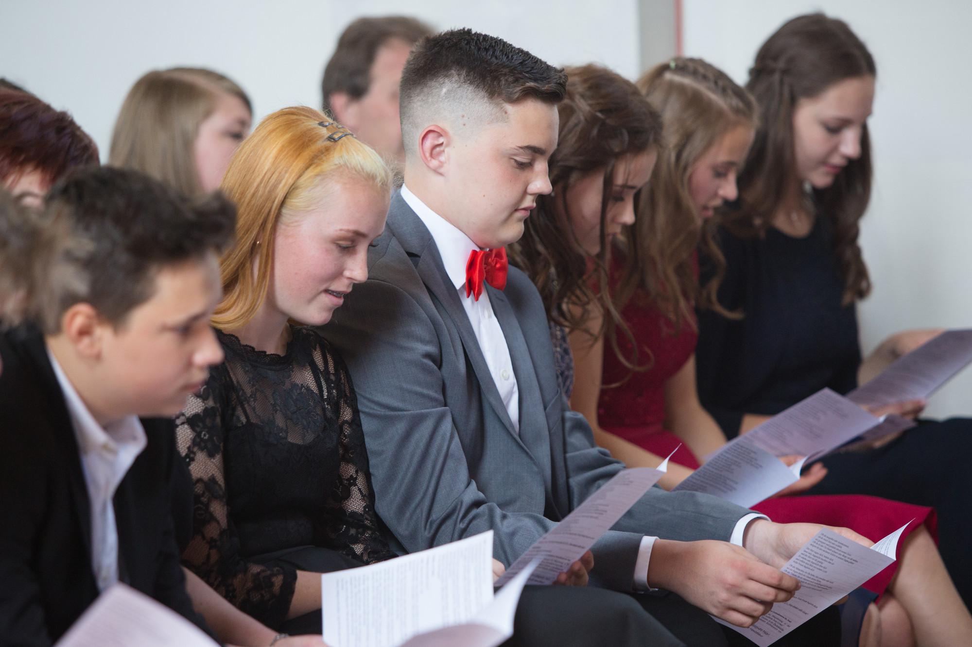 Jugendliche sitzen in einer Kirchenbank und singen