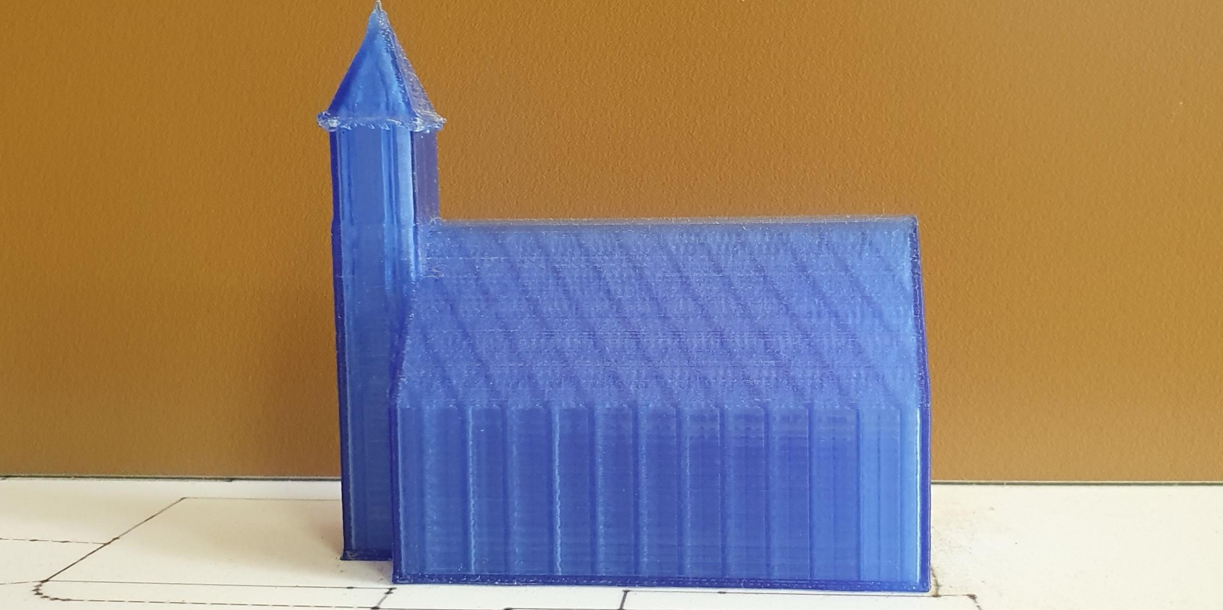 Ein blaues Modell einer Kirche mit einem Turm steht auf einem skizzierten Stadtplan.