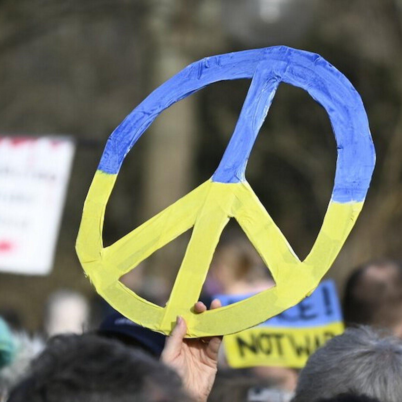 Ein buntes Friedenszeichen wird bei einer Demonstration für Frieden in der Ukraine hochgehalten.
