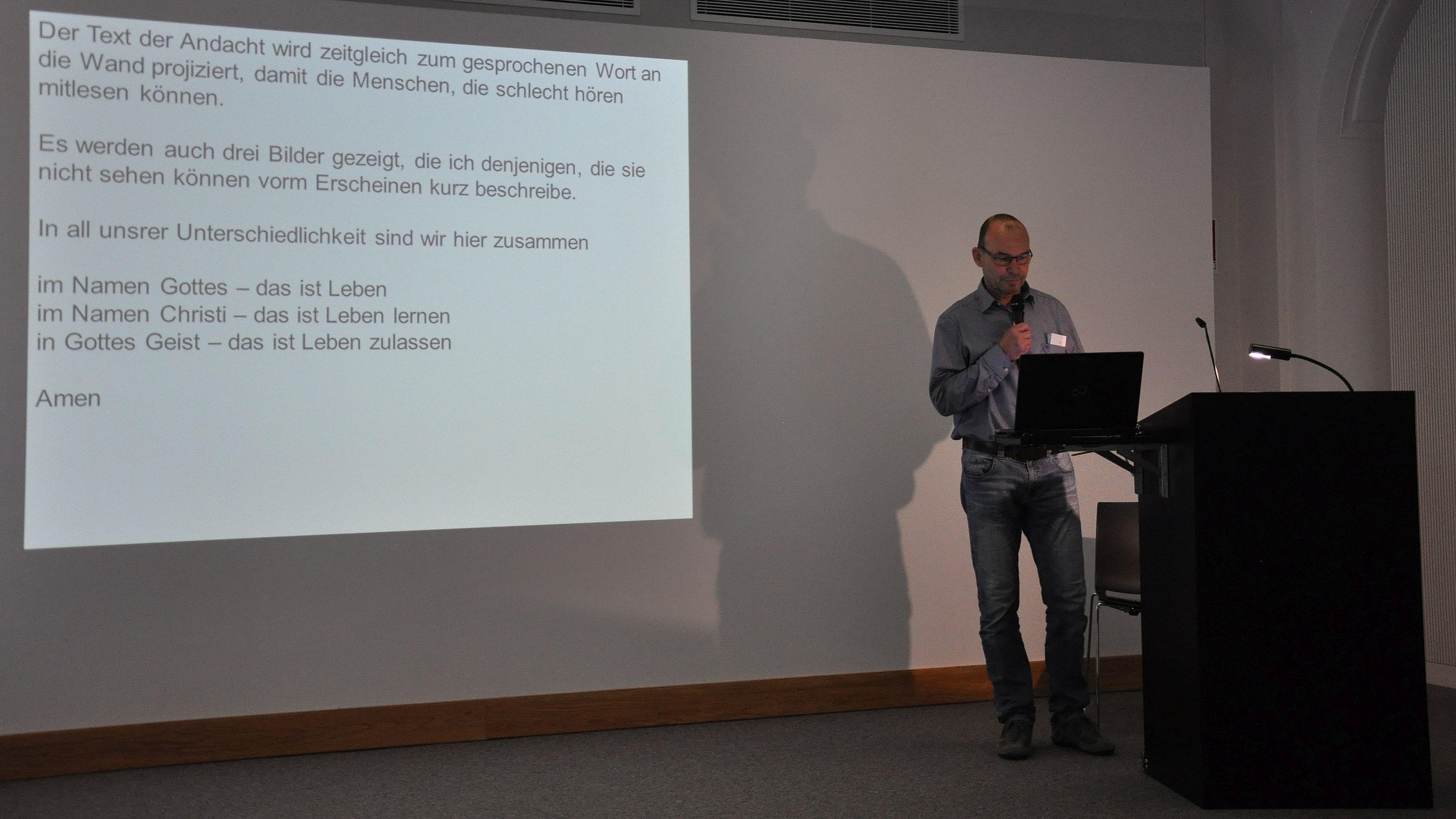Hans-Gunther Seifert am Lesepult mit Mikrofon.