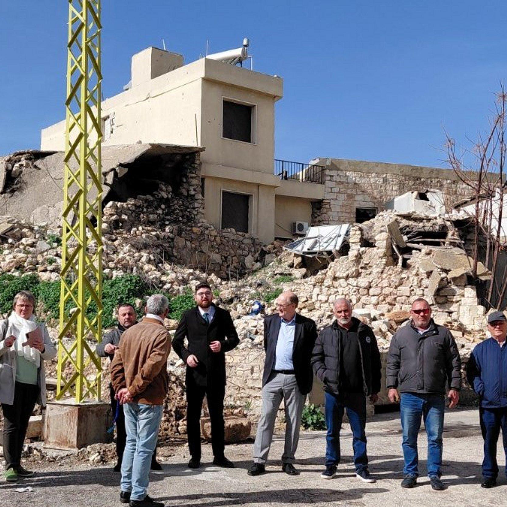 Zerstörte Kirche, davor eine Gruppe von Personen.