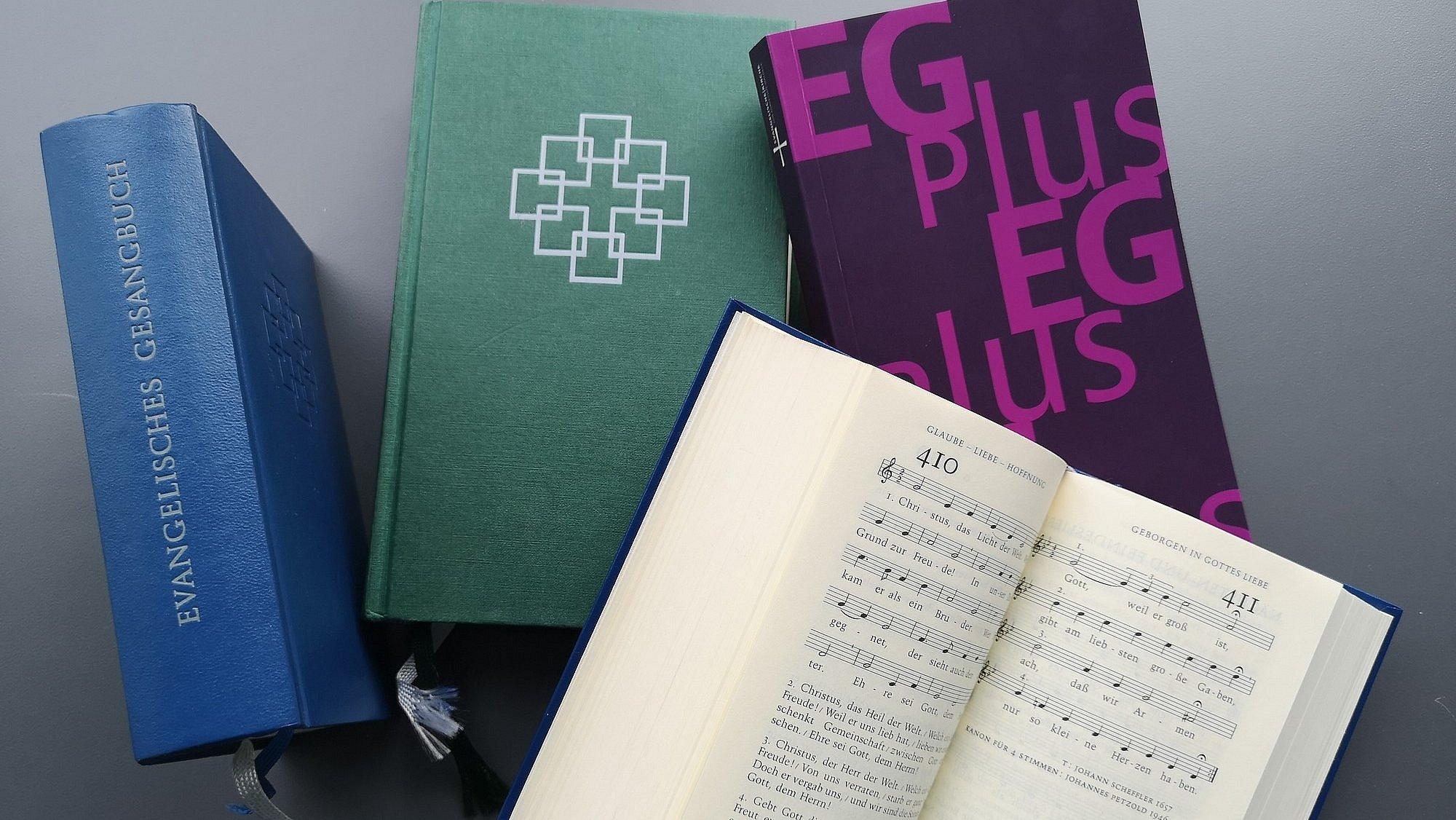 Mehrere Ausgaben, ein Gesangbuch ist aufgeschlagen.