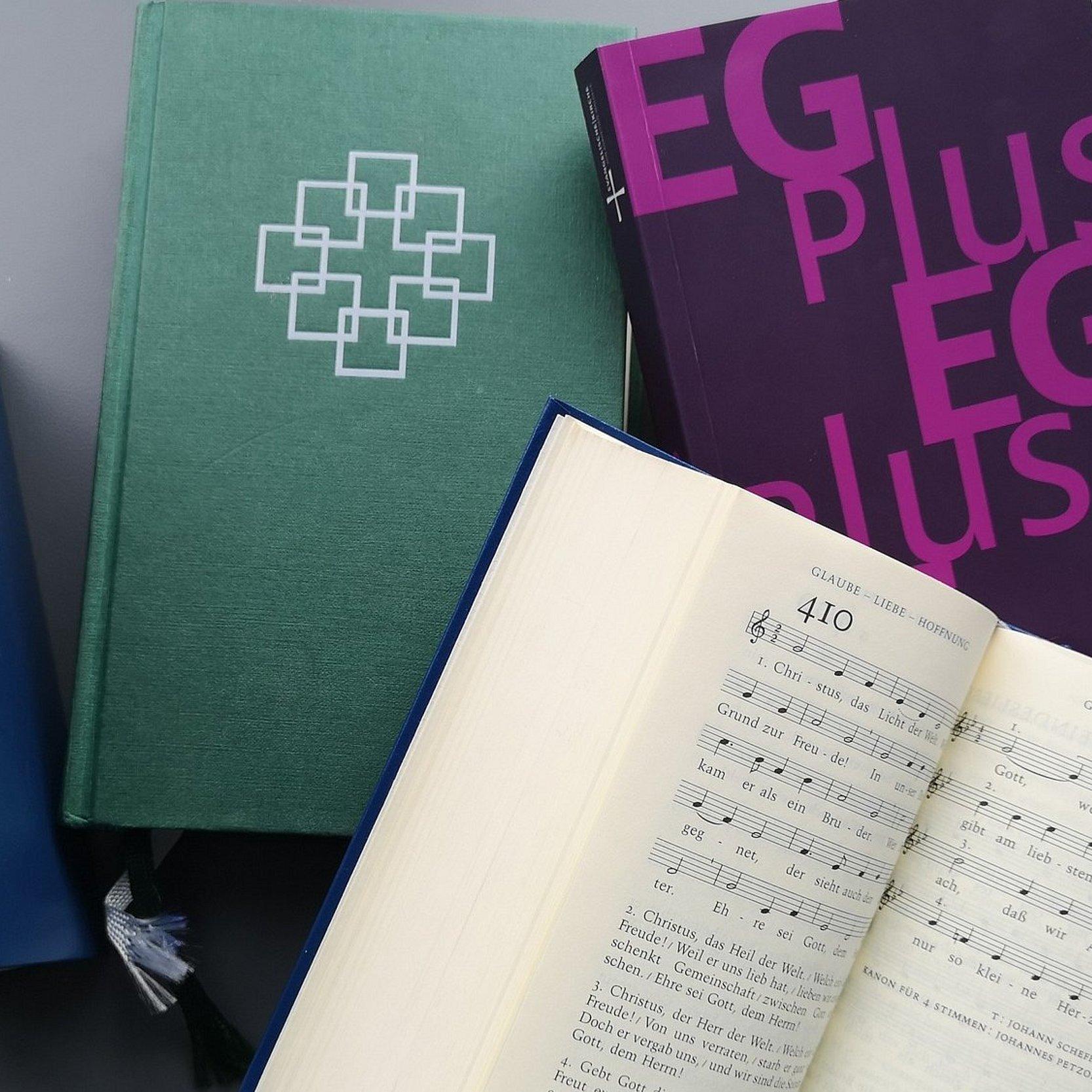 Mehrere Ausgaben, ein Gesangbuch ist aufgeschlagen.