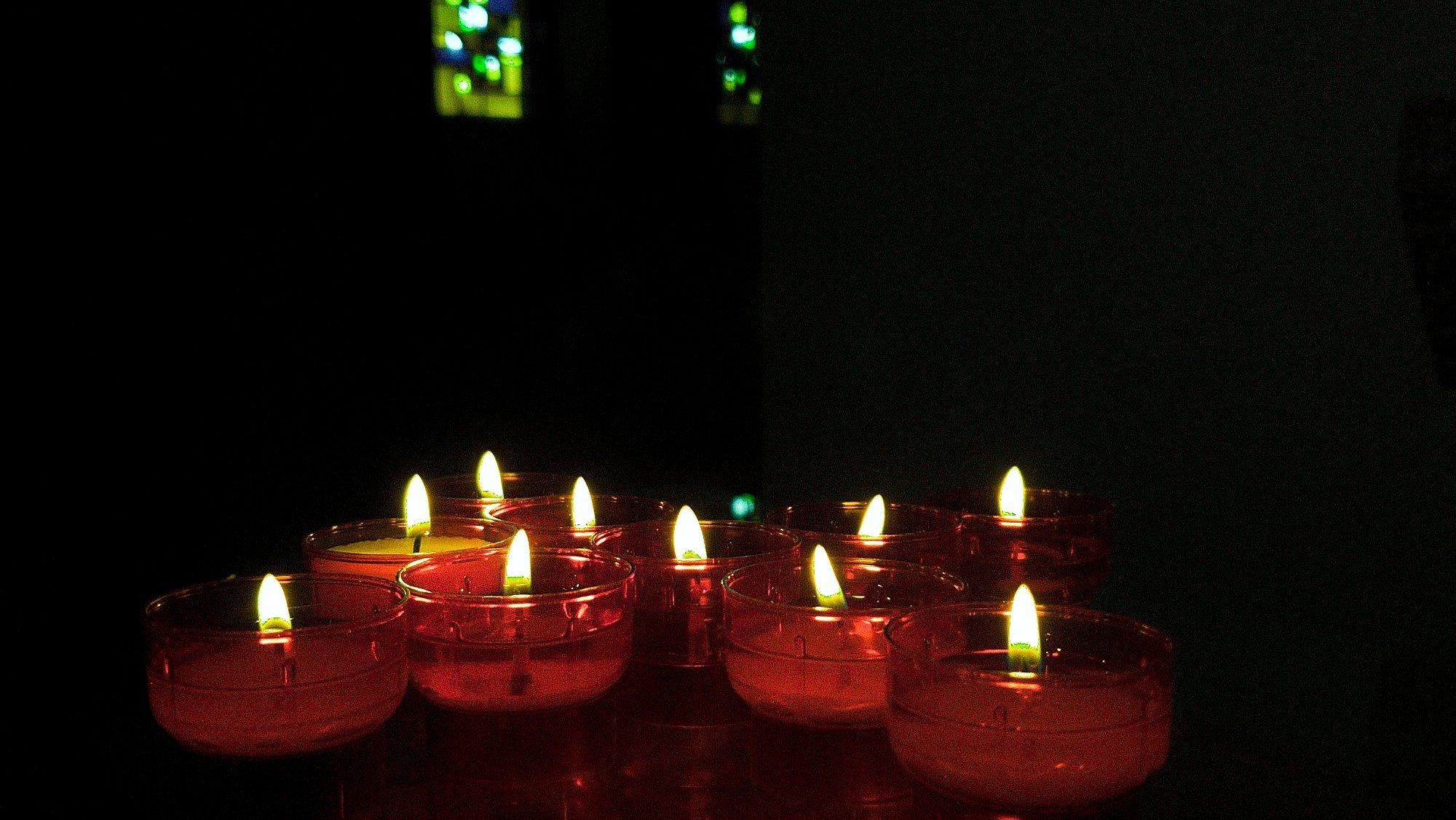Kerzen leuchten in dunkler Kirche