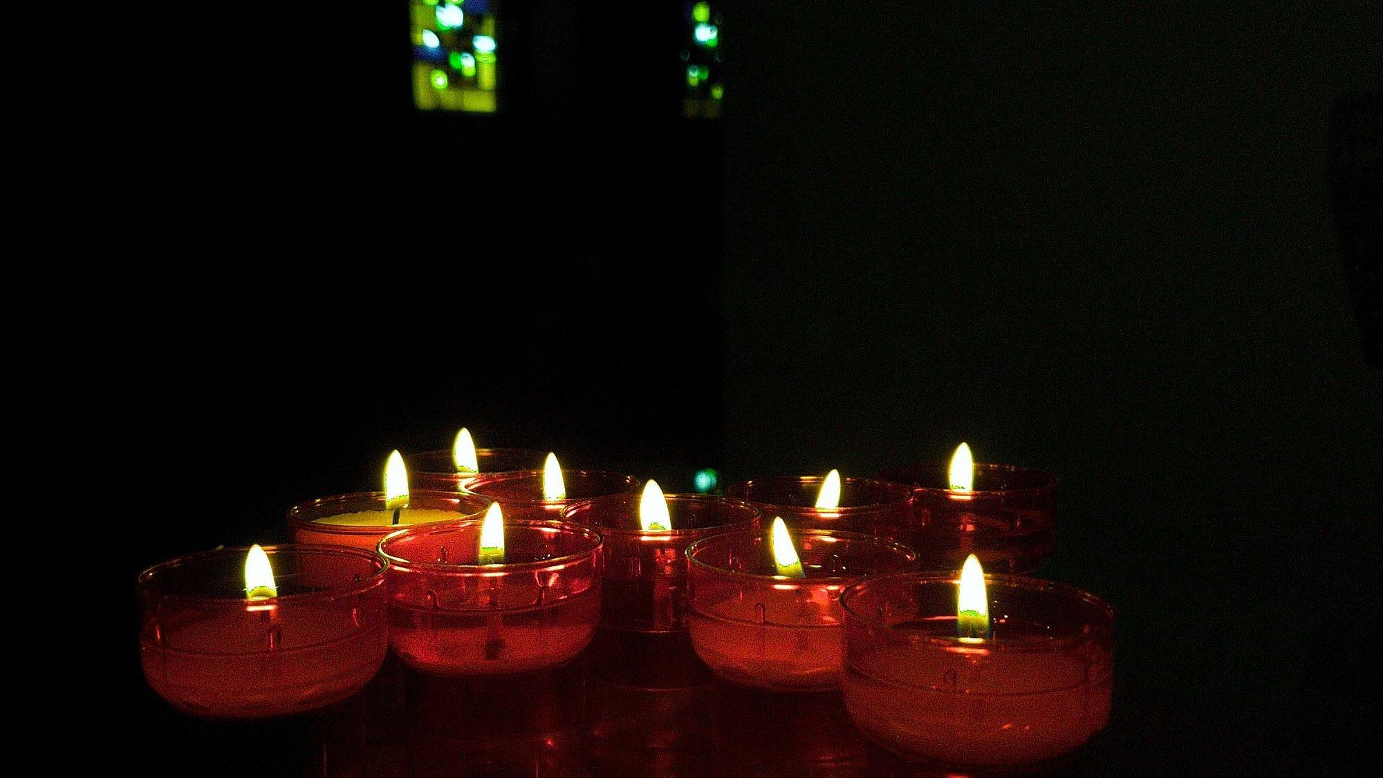 Kerzen leuchten in dunkler Kirche