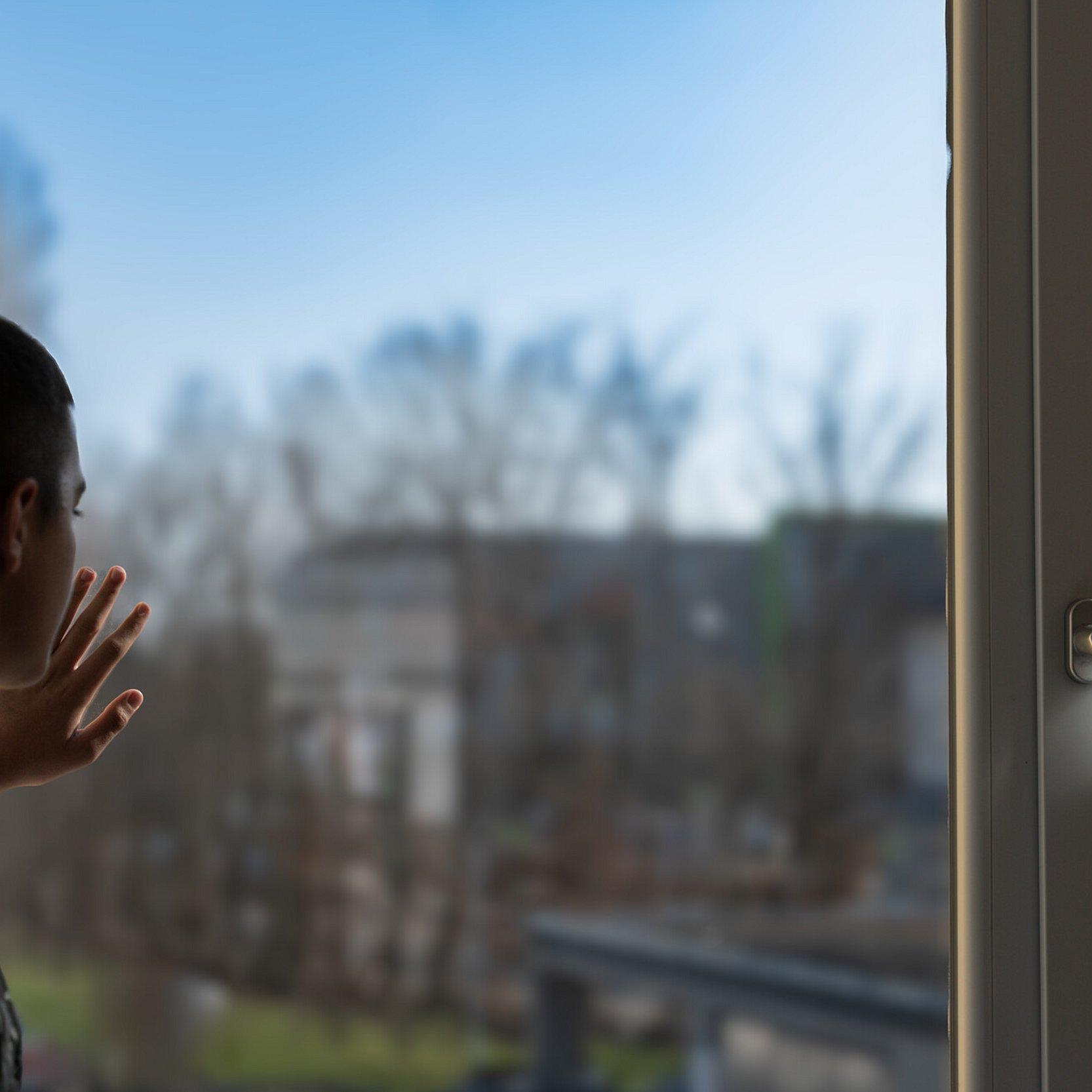 Junger Mann schaut aus dem Fenster