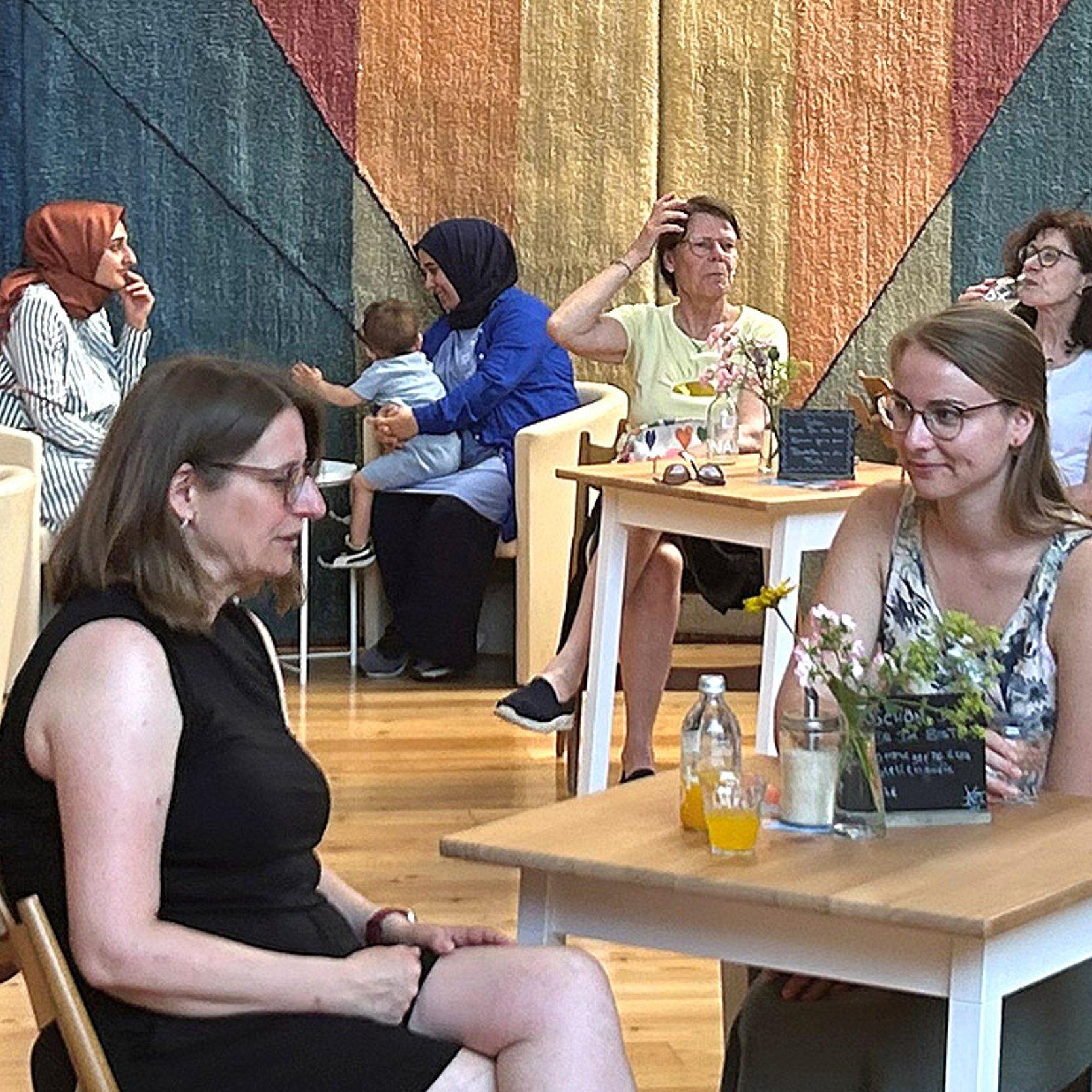Menschen, die an Tischen sitzen in einem Kirchenraum, der mit Holz ausgekleidet ist
