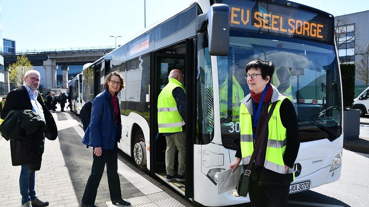 Bus der FraPort, Personen steigen ein. Display zeigt an Ev. Seelsorge