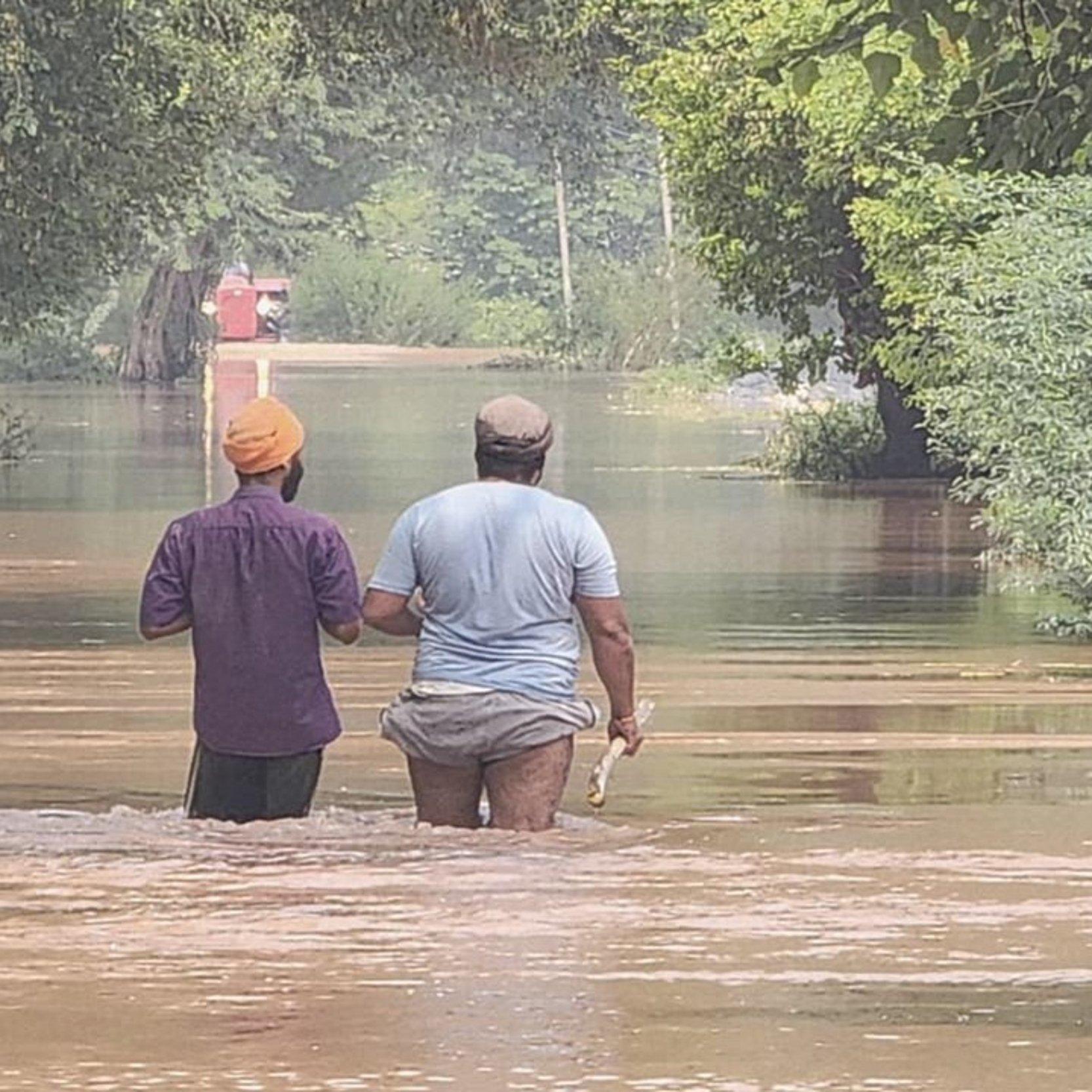 Zwei Männer waten in braunem Wasser