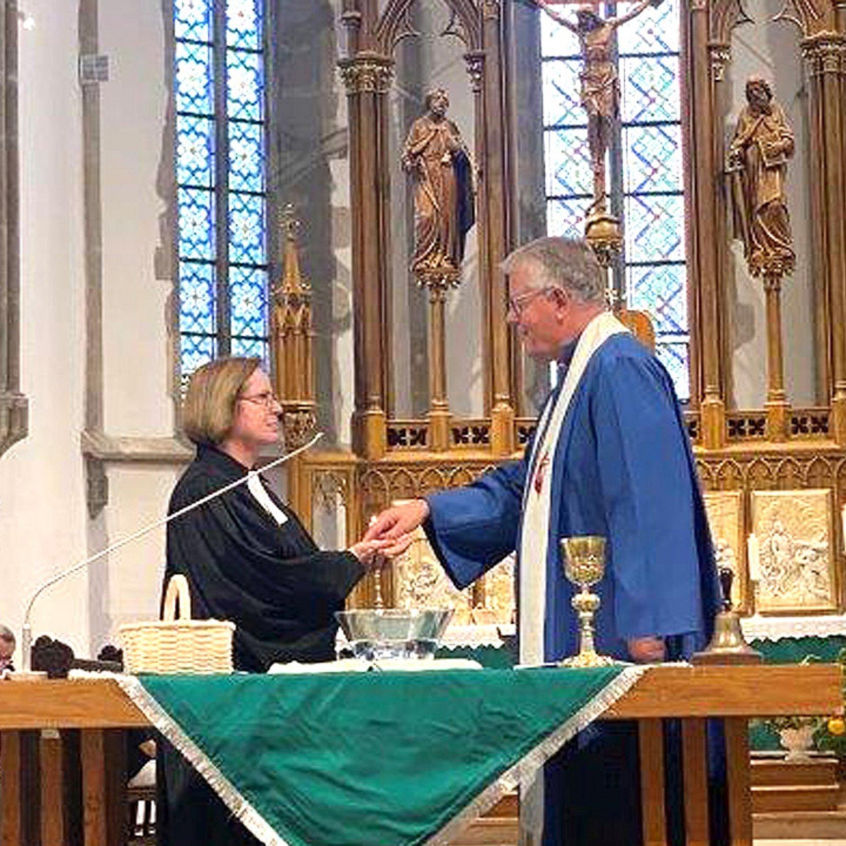 Ulrike Scherf wird hinter einem Altar beglückwünscht