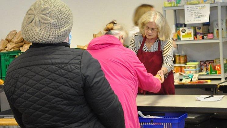 Zwei Frauen holen sich Lebensmittel an der Verkaufstheke ab. In Hintergrund einige kleine Lebensmittelregale