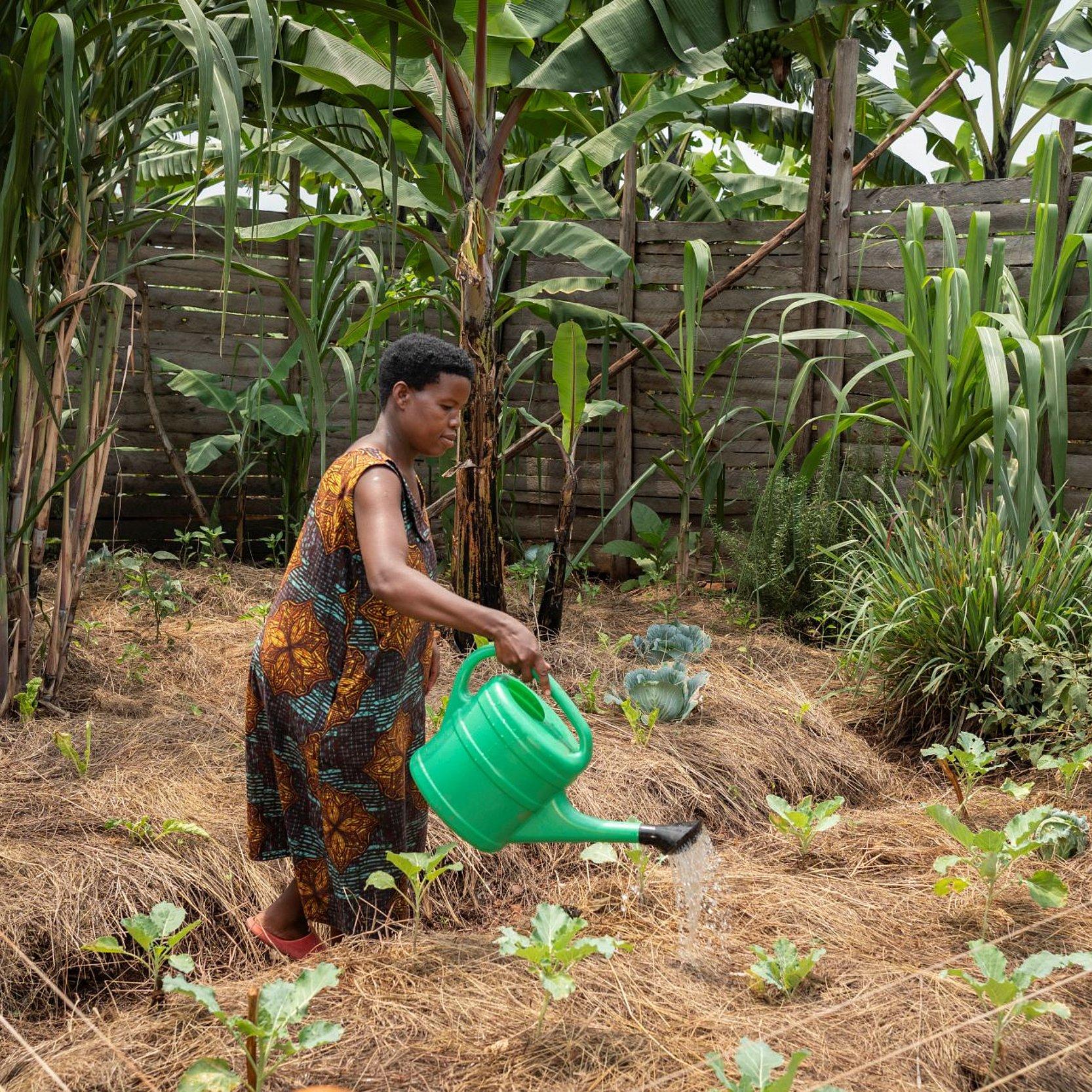 Frau mit Gießklanne im Garten
