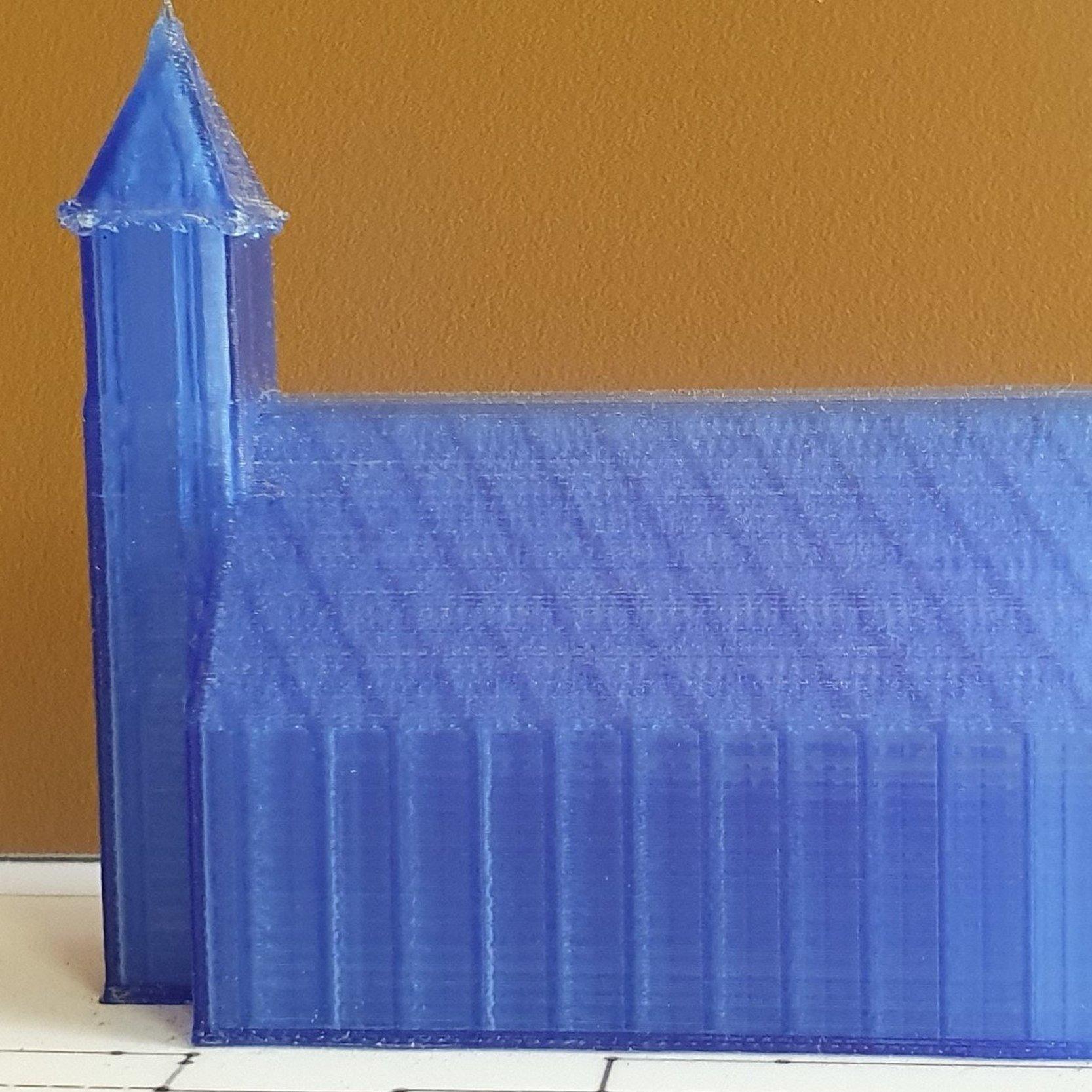 Ein blaues Modell einer Kirche mit einem Turm steht auf einem skizzierten Stadtplan.