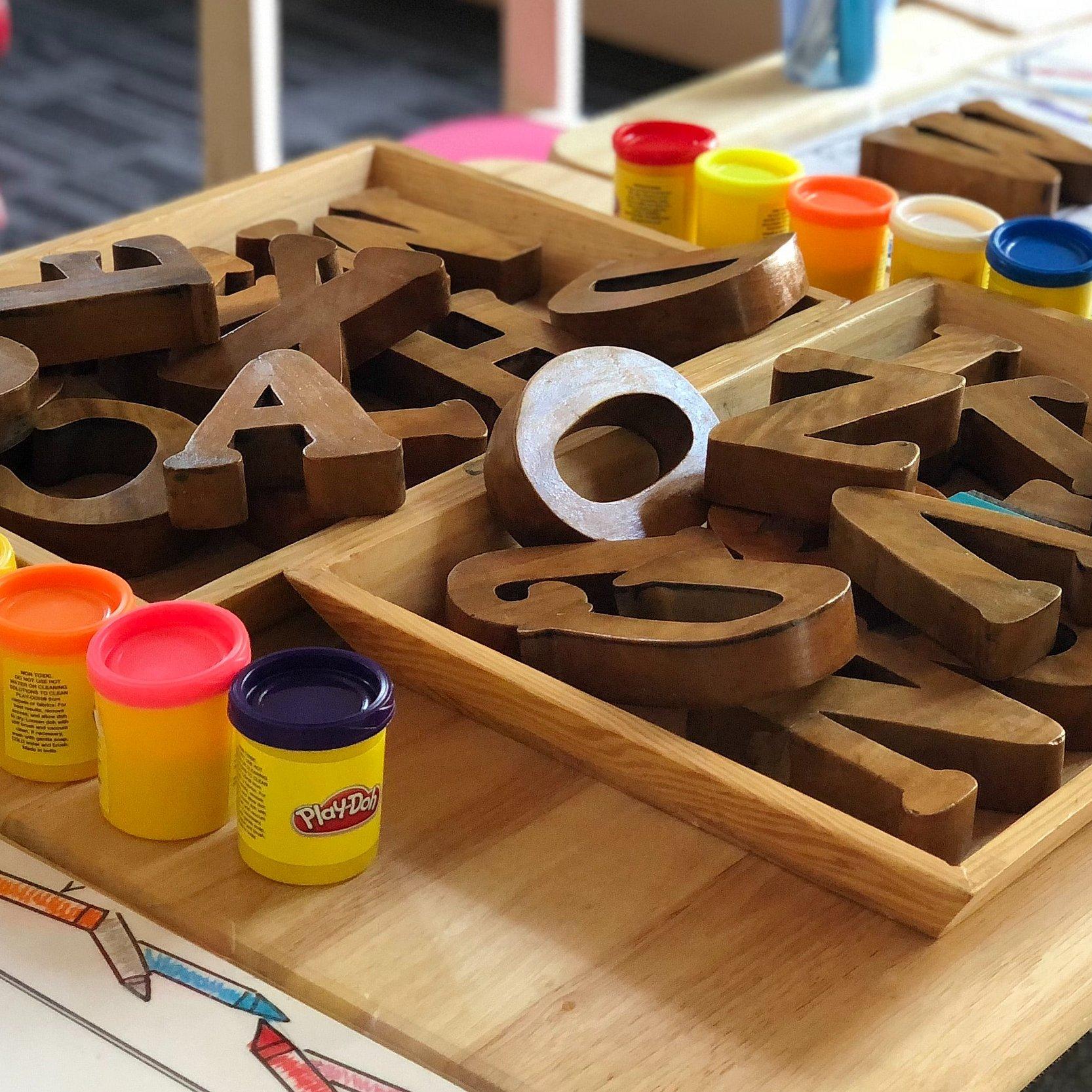 Holzbuchstaben und Knete auf einem Tisch in der Kita.