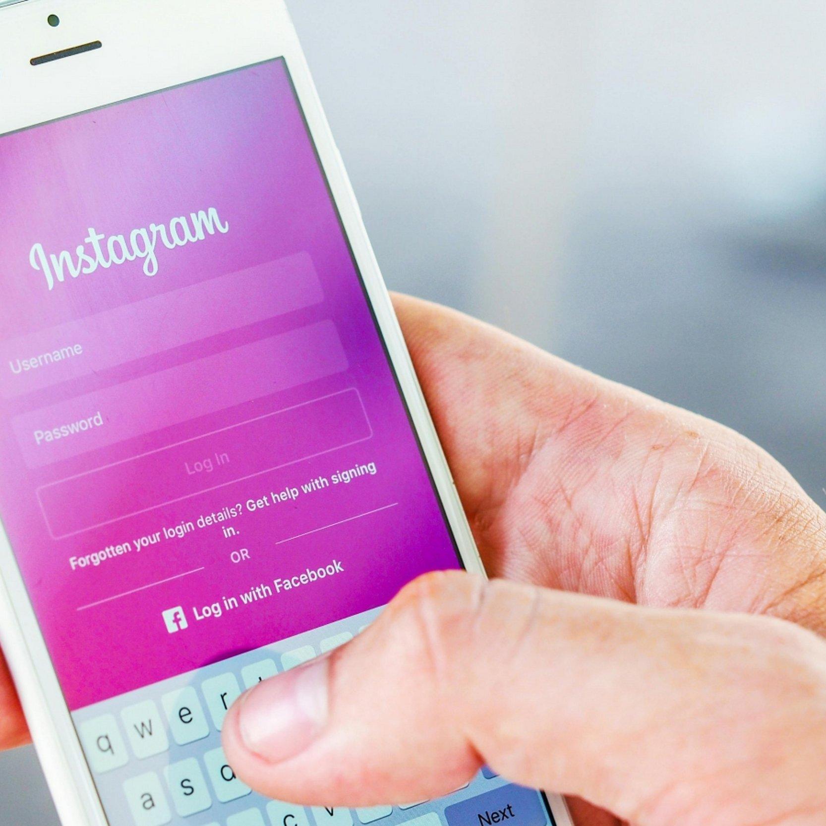 Hand mit Smartpone auf dem Instagram-Login angezeigt wird