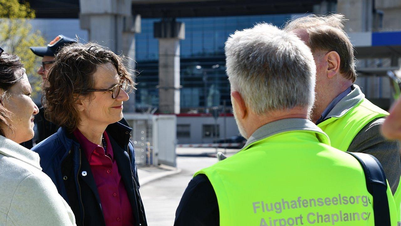 4 Personen im Gespräch im Außenbereich des Flughafens