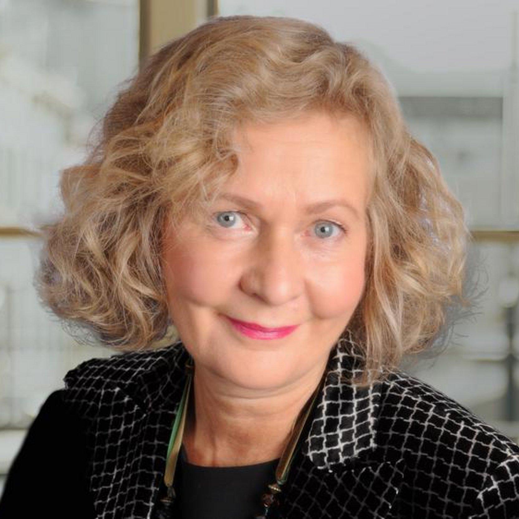 Renate Jost mit lockigem halblangen blonden Haar lächelt in die Kamera