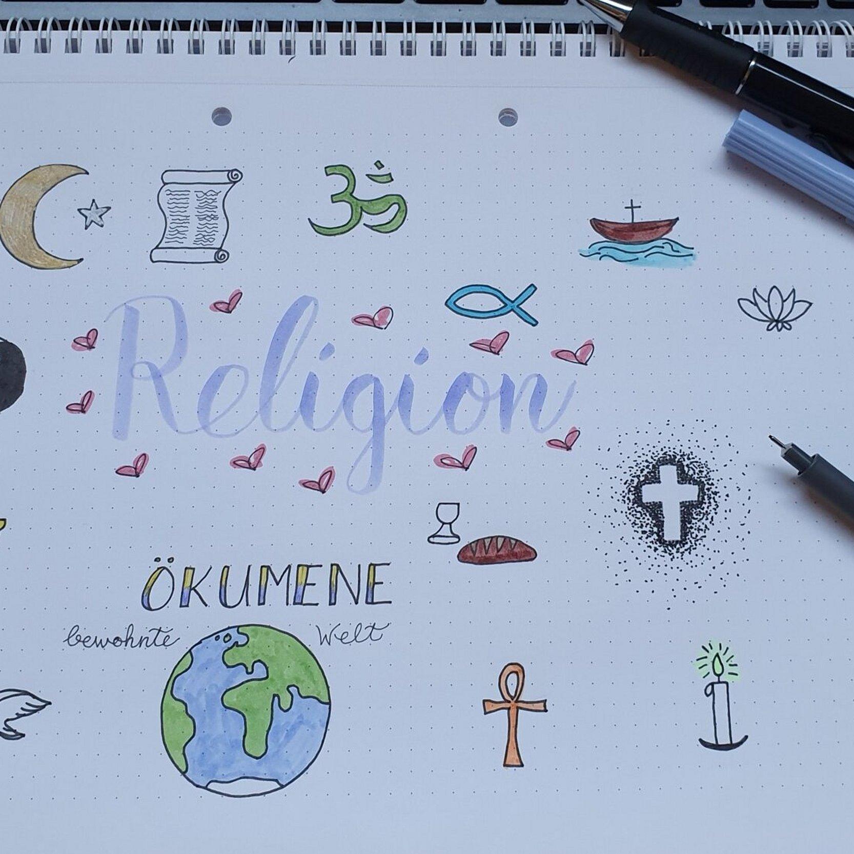 Auf einen Zeichenblock gemalte Symbole der Weltreligionen