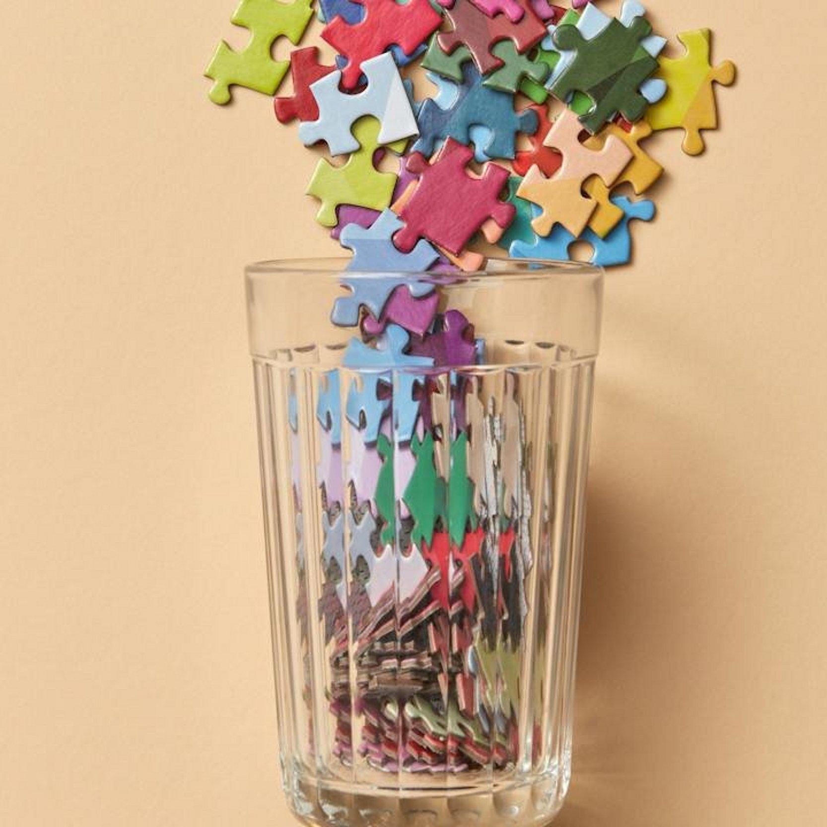 Viele Puzzleteile fallen in ein Glas