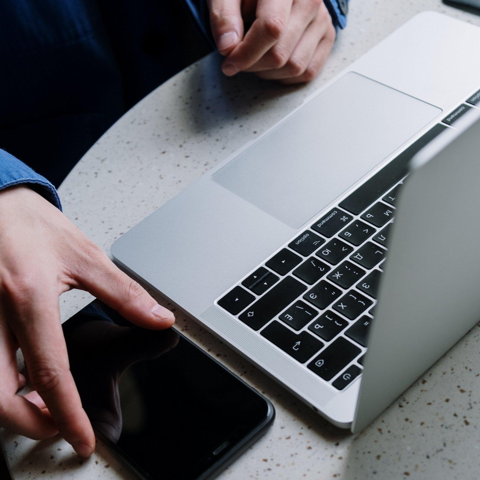 Hände am Notebook und Smartphone