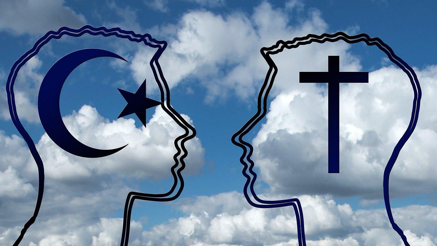 Vor einem blauen Himmel mit Wolken sieht man die Umrisse von zwei sich zugewandten Köpfen. In ihnen sind zu sehen: Hilal (Mondsichel) und ein fünfzackiger Stern und ein Kreuz.
