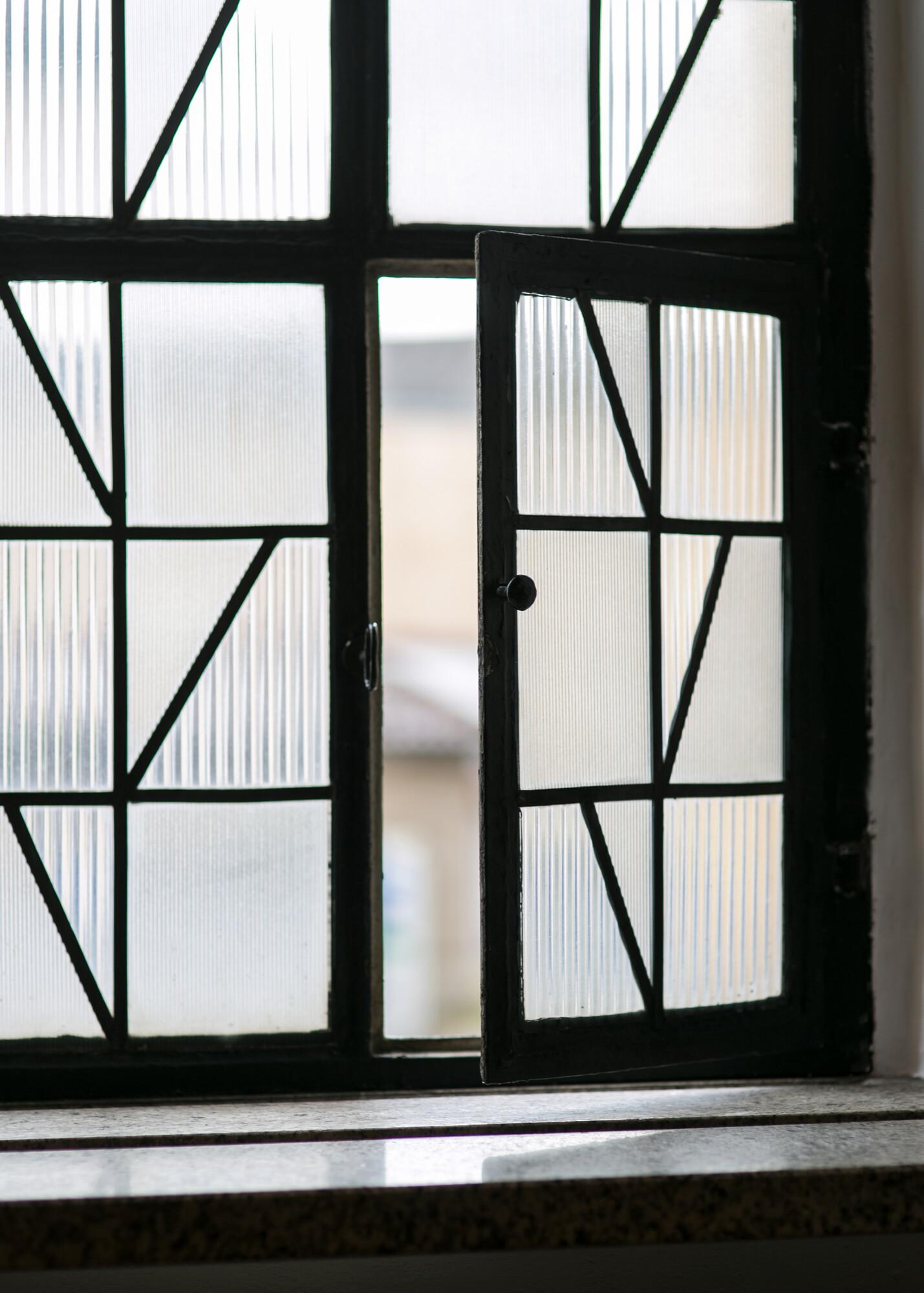 Fenserfront aus Reliefglas. Ein Teilfenster davon ist geöffnet