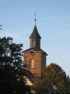 Kirchturm zwischen grünen Baumwipfeln