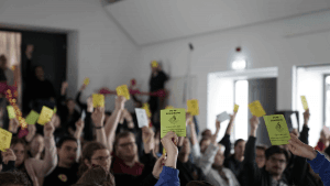 Man sieht wie viele Menschen eine Stimmkarte in die Höhe heben