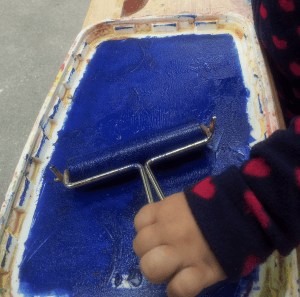 Eine Farbwalze wird in blauer Farbe gewälzt