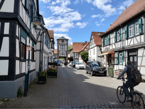 Eine Straße, eingerahmt von Fachwerkhäusern, an deren Ende ein Ortseingangsturm steht.