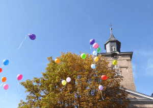 Blick auf die Kirche mit bunten Luftballons, die in den Himmel steigen.