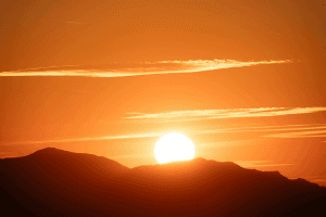 Feurige Sonne geht hinter Bergrücken auf