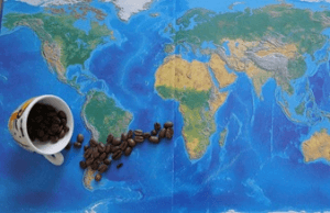 Umgekippte Kaffeetasse, aus der sich Kaffeebohnen über eine Weltkarte verteilen