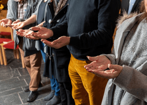 Menschen stehen im Gebet zusammen