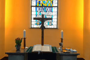 Altar der Stadtkirche mit Kreuz und Bibel, 2 Kerzen und rotem Tulpenstrauß
