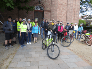 Eine Gruppe von Radlern steht vor der Ev. Kirche Liederbach