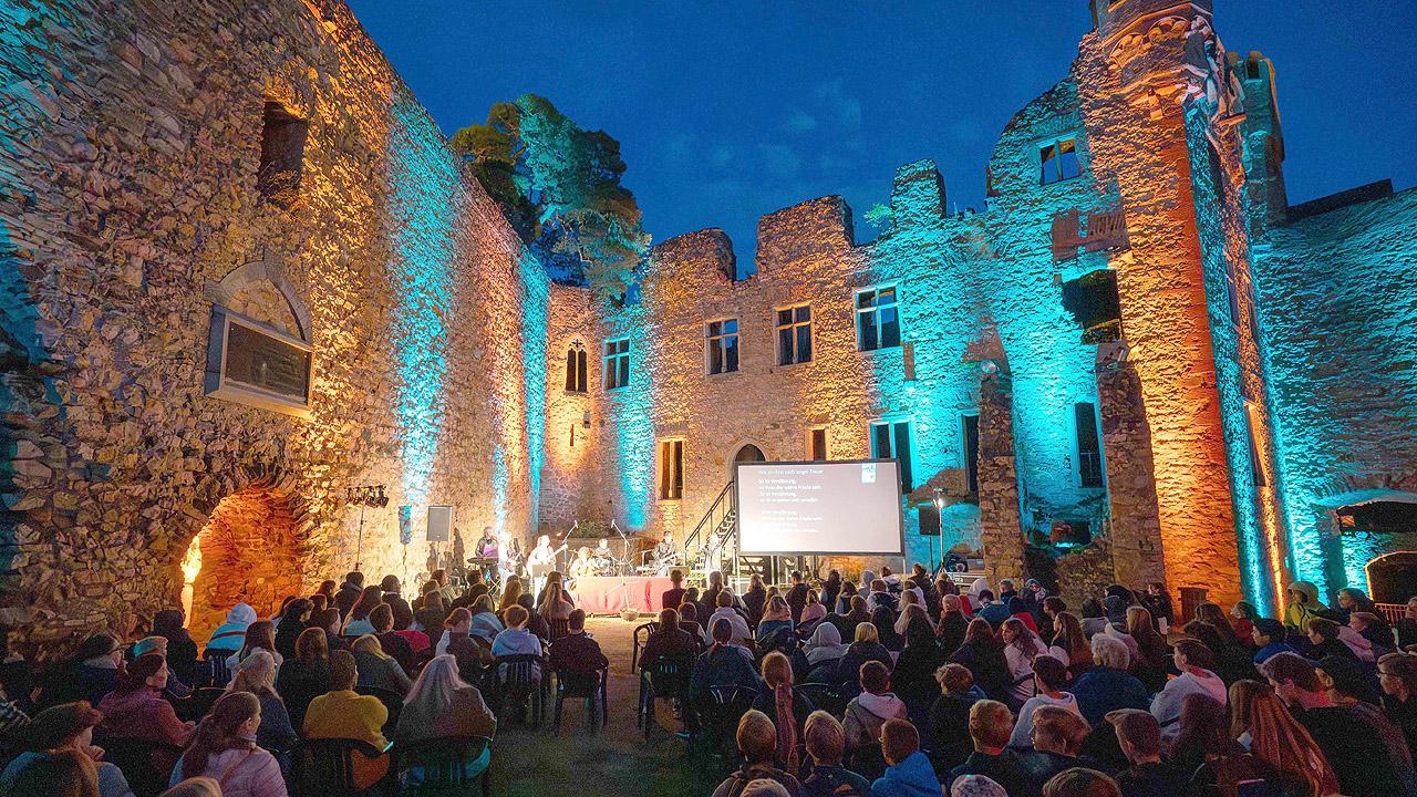 Jugendgottesdienst Beleuchtete Bühne in Schlossruine, davor viele Jugendliche