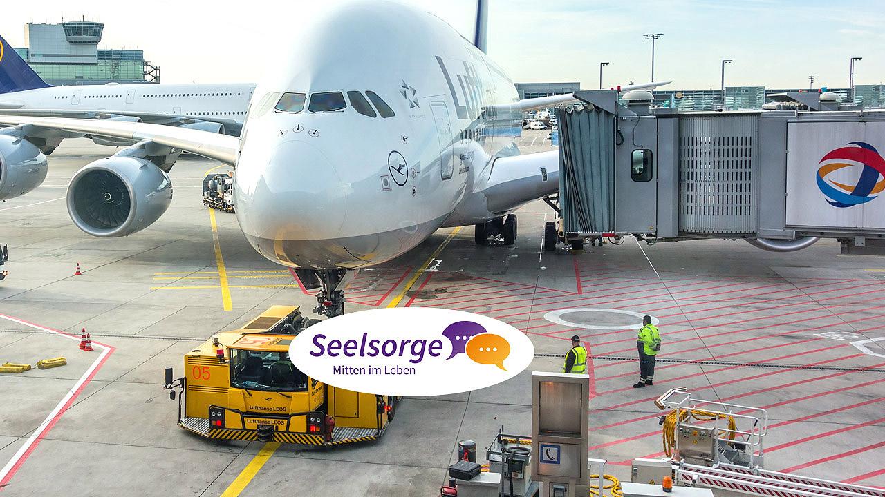 Flughafenseelsorge Rollfeld mit Flugzeug und Beschäftigten in Schutzwesten