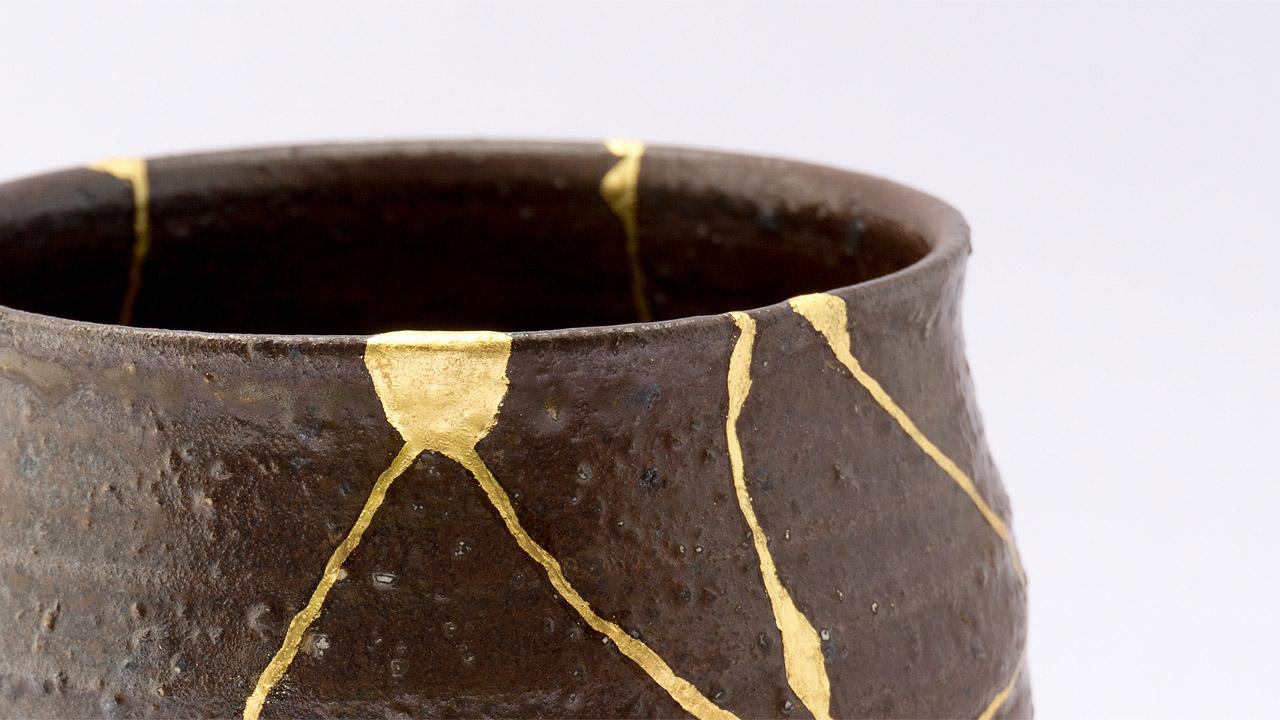 Kintsugi Bruchstellen aus Gold eines grau-braunen Gefäßes