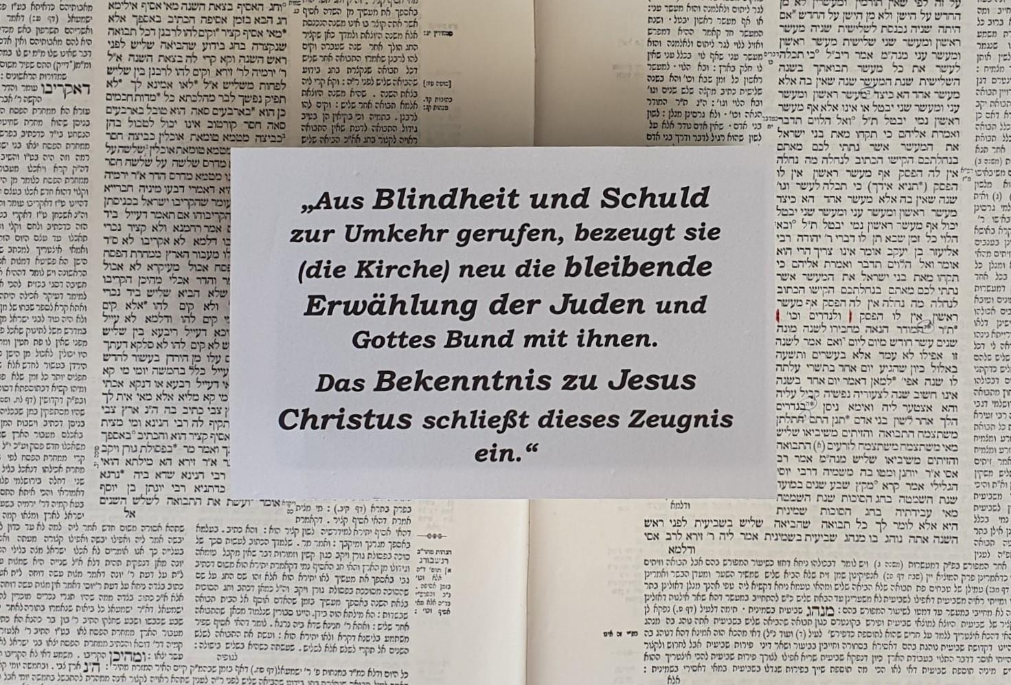 Zu sehen ist der Abschnitt aus dem Grundartikel der EKHN. Im Hintergrund eine Seite aus dem Babylonischen Talmud.