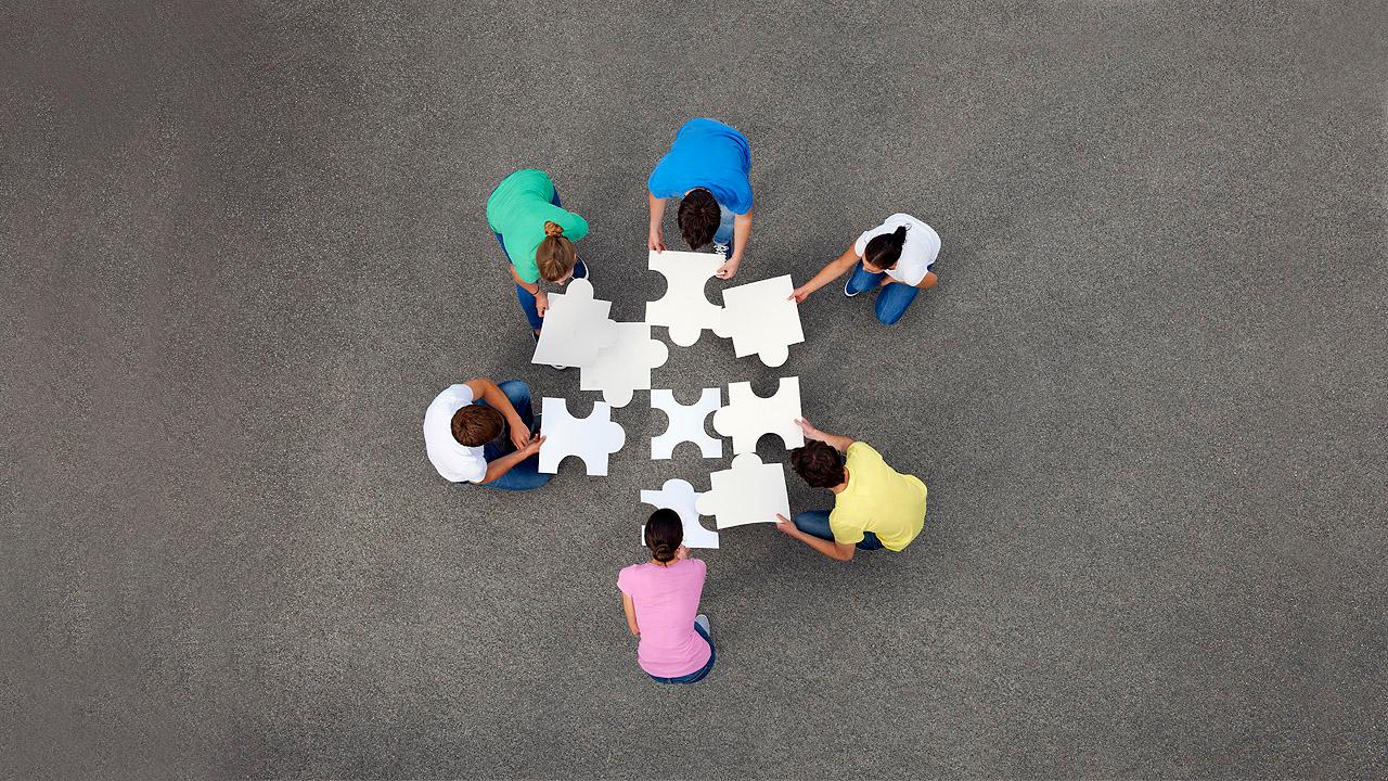 Menschen legen große Puzzleteile zusammen