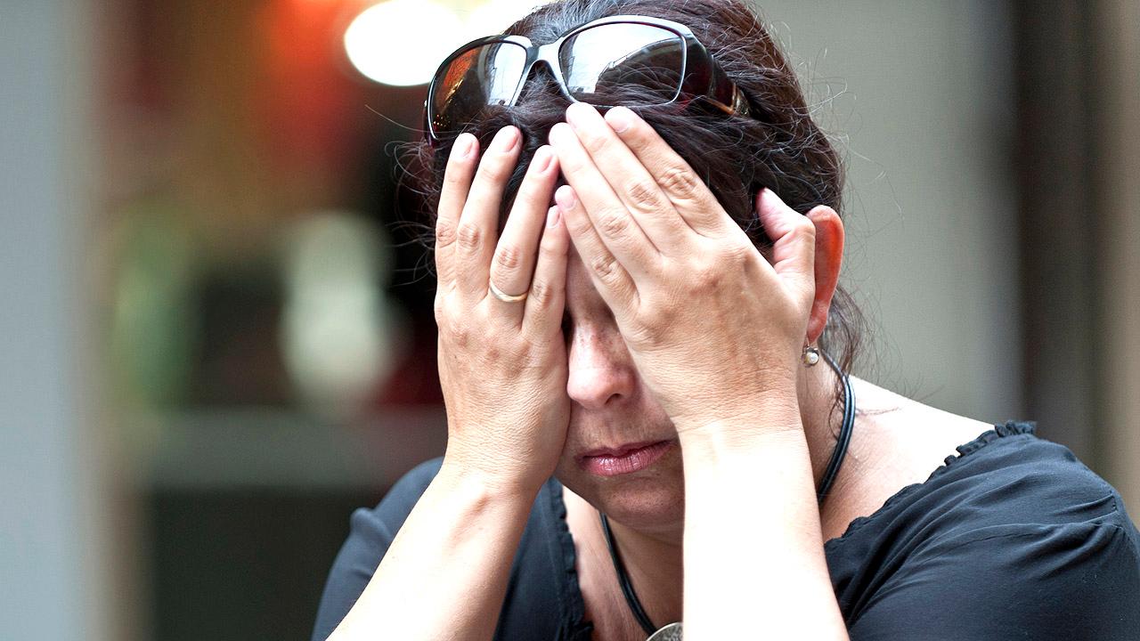 Eine Frau mittleren Alters hält die Hände vor das Gesicht