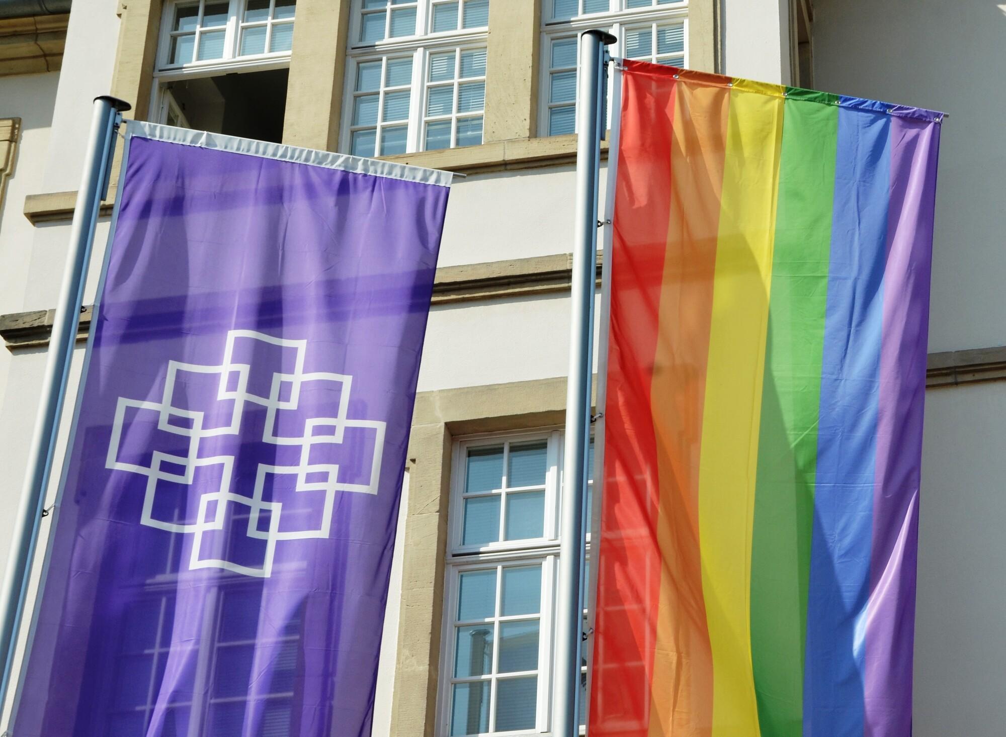 Fahnen vor der Kirchenverwaltung der EKHN Vor der Kirchenverwaltung der EKHN wurden neben der lila EKHN-Fahne mit Facettenkreuz anlässlich des CSD auch eine Regenbogenfahne gehisst.