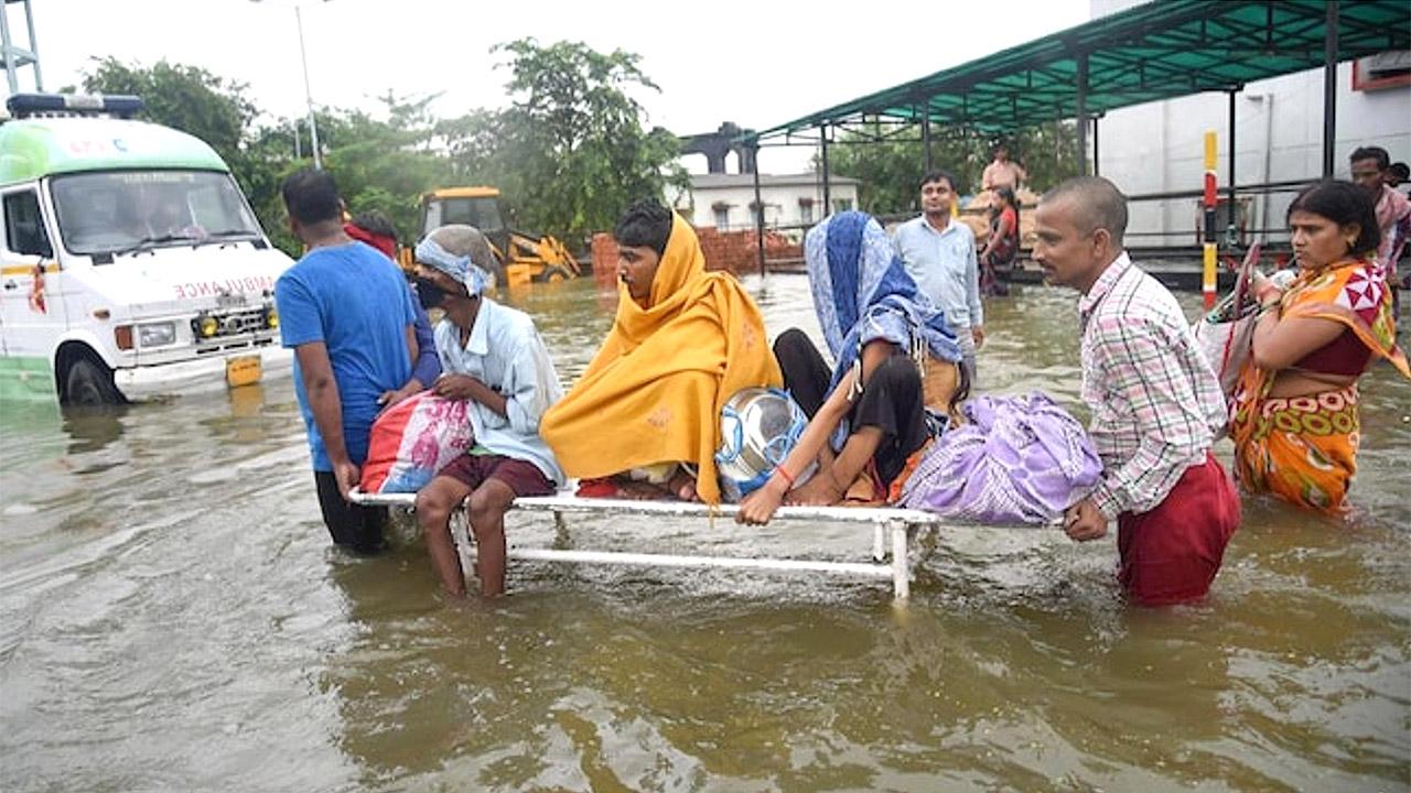 Überschwemmung in Indien Männer tragen Menschen auf einem Brett durch die Fluten