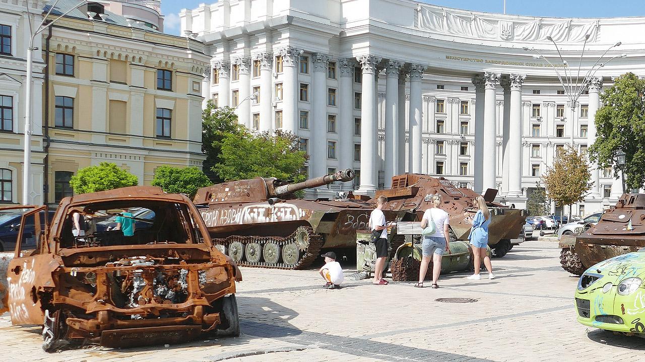 Zerstörte Panzer und Autos vor einem prächtigen weißen Gebäude