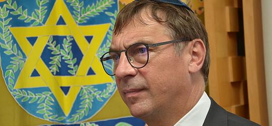 Rechts im Bild ist der EKHN-Kirchenpräsident Volker Jung zu sehen. Im Hintergrund links sieht man einen goldenen Davidstern, auf einem Vorhang vor dem Schrank mit den Torah-Rollen. .